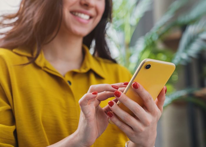 Cropped image of happy girl using smartphone device while chilling at home