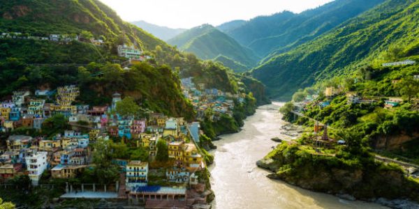 Confluence of two rivers Alaknanda and Bhagirathi give rise to the holy river of Ganga / Ganges at one of the five Prayags called Dev Prayag. Lush greenery in monsoons on the mountains. sunrise. India